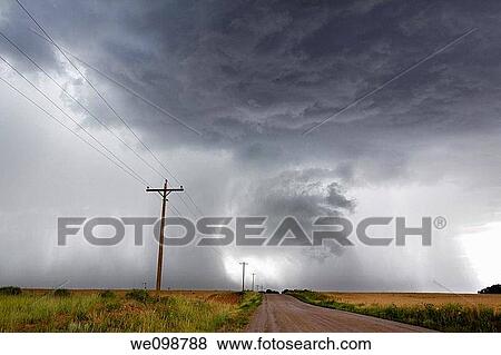 Angry looming cumulus thunder clouds releasing rain in a rural thunderstorm with dirt road leading into the distance View Large Photo Image Stock Photo - Angry looming cumulus thunder clouds releasing rain in a rural thunderstorm with dirt road leading into the distance. Fotosearch