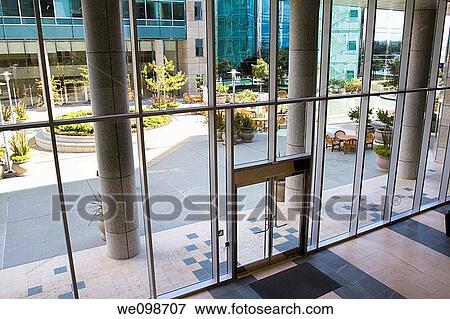 Attractive courtyard patio area as seen through the glass entrance to a modern office building complex in Silicon Valley. San Mateo, California, USA. View Large Photo Image Stock Photo - Attractive courtyard patio area as seen through the glass entrance to a modern office building complex in Silicon Valley. San Mateo, California, USA.. Fotosearch