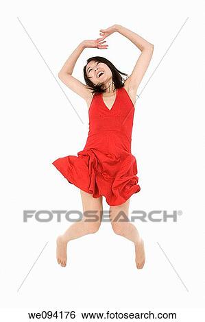 Stock Photograph - Beautiful Asain woman in a red sundress jumping on a white background. Fotosearch