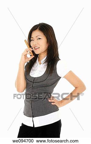 Stock Image - Beautiful Asian businesswoman holding a cigar on a white background. Fotosearch