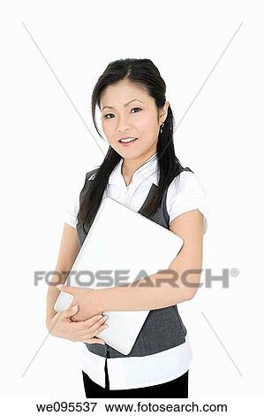 Beautiful Asian businesswoman holding a laptop computer View Large Photo Image Stock Photo - Beautiful Asian businesswoman holding a laptop computer. Fotosearch