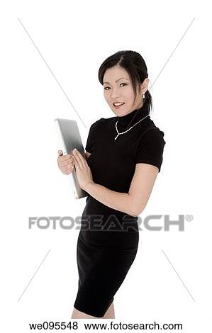 Beautiful Asian businesswoman holding a laptop computer View Large Photo Image Stock Photo - Beautiful Asian businesswoman holding a laptop computer. Fotosearch