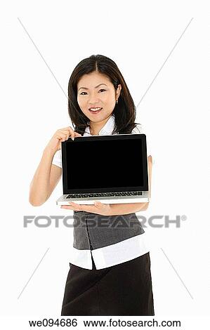 Beautiful Asian businesswoman holding a laptop computer and showing the screen View Large Photo Image Stock Photograph - Beautiful Asian businesswoman holding a laptop computer and showing the screen. Fotosearch