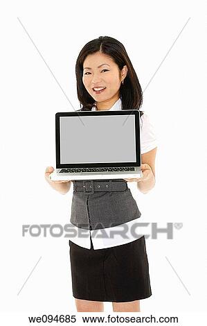 Stock Photography - Beautiful Asian businesswoman holding a laptop computer and showing the screen with clipping path. Fotosearch