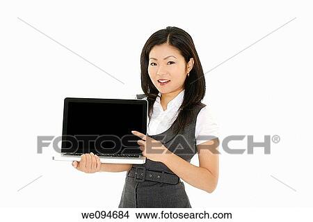Beautiful Asian businesswoman holding and pointing at a laptop computer with clipping path View Large Photo Image Picture - Beautiful Asian businesswoman holding and pointing at a laptop computer with clipping path. Fotosearch