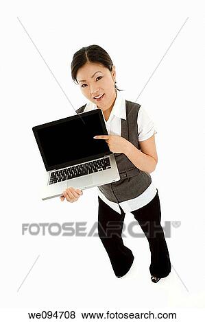 Beautiful Asian businesswoman holding and pointing at a laptop computer View Large Photo Image Stock Photo - Beautiful Asian businesswoman holding and pointing at a laptop computer. Fotosearch