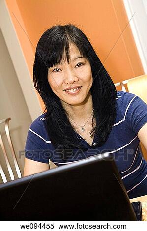 Beautiful Asian woman working on a laptop computer View Large Photo Image Stock Photography - Beautiful Asian woman working on a laptop computer. Fotosearch
