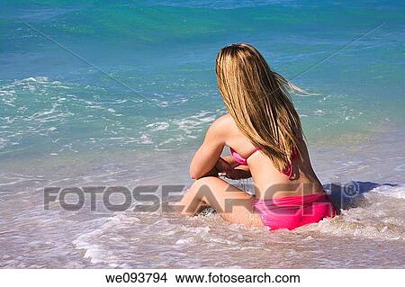 Beautiful Caucasian female teenage sitting in the surf wearing a colorful pink bikini View Large Photo Image Picture - Beautiful Caucasian female teenage sitting in the surf wearing a colorful pink bikini. Fotosearch