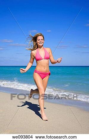 Beautiful Caucasian female teenage running through to surf wearing a colorful bikini View Large Photo Image Picture - Beautiful Caucasian female teenage running through to surf wearing a colorful bikini. Fotosearch