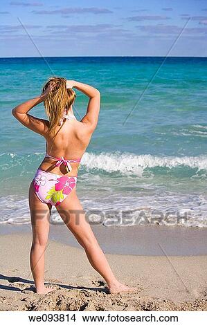 Beautiful Caucasian female teenage standing in the surf wearing a colorful one piece swimsuit View Large Photo Image Picture - Beautiful Caucasian female teenage standing in the surf wearing a colorful one piece swimsuit. Fotosearch