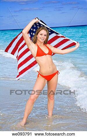Beautiful Caucasian female teenage standing on the beach and holding an United States Flag while wearing a red bikini View Large Photo Image Stock Image - Beautiful Caucasian female teenage standing on the beach and holding an United States Flag while wearing a red bikini. Fotosearch