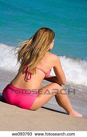 Beautiful Caucasian female teenage sitting in the surf wearing a colorful pink bikini View Large Photo Image Stock Image - Beautiful Caucasian female teenage sitting in the surf wearing a colorful pink bikini. Fotosearch
