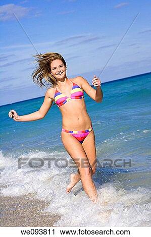Beautiful Caucasian female teenage running through to surf wearing a colorful bikini View Large Photo Image Stock Image - Beautiful Caucasian female teenage running through to surf wearing a colorful bikini. Fotosearch