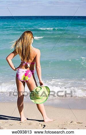 Beautiful Caucasian female teenage standing in the surf wearing a colorful one piece swimsuit View Large Photo Image Stock Image - Beautiful Caucasian female teenage standing in the surf wearing a colorful one piece swimsuit. Fotosearch