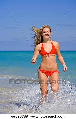 Beautiful Caucasian female teenage running through to surf wearing a colorful bikini View Large Photo Image Stock Photo - Beautiful Caucasian female teenage running through to surf wearing a colorful bikini. Fotosearch
