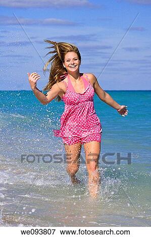 Beautiful Caucasian female teenage running through to surf wearing a colorful bikini View Large Photo Image Stock Photo - Beautiful Caucasian female teenage running through to surf wearing a colorful bikini. Fotosearch