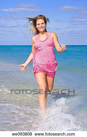 Beautiful Caucasian female teenage running through to surf wearing a colorful sundress View Large Photo Image Stock Photo - Beautiful Caucasian female teenage running through to surf wearing a colorful sundress. Fotosearch