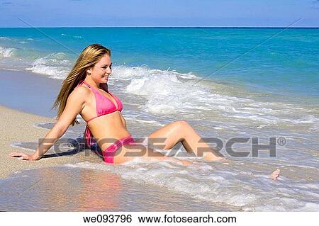 Beautiful Caucasian female teenage sitting in the surf wearing a colorful pink bikini View Large Photo Image Stock Photograph - Beautiful Caucasian female teenage sitting in the surf wearing a colorful pink bikini. Fotosearch