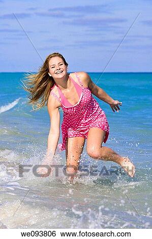 Beautiful Caucasian female teenage running through to surf wearing a colorful sundress and bikini View Large Photo Image Stock Photograph - Beautiful Caucasian female teenage running through to surf wearing a colorful sundress and bikini. Fotosearch