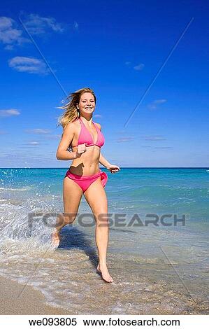 Beautiful Caucasian female teenage running through to surf wearing a colorful bikini View Large Photo Image Stock Photography - Beautiful Caucasian female teenage running through to surf wearing a colorful bikini. Fotosearch