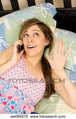 Beautiful Caucasian female teenager laying in bed talking with friends in a cell phone View Large Photo Image Stock Image - Beautiful Caucasian female teenager laying in bed talking with friends in a cell phone. Fotosearch