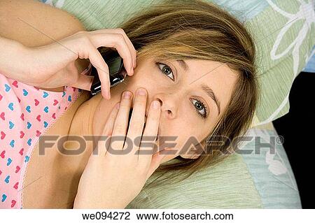 Beautiful Caucasian female teenager laying in bed talking with friends in a cell phone View Large Photo Image Stock Image - Beautiful Caucasian female teenager laying in bed talking with friends in a cell phone. Fotosearch