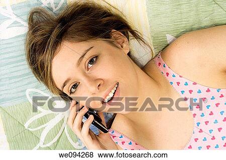 Beautiful Caucasian female teenager laying in bed talking with friends in a cell phone View Large Photo Image Stock Photo - Beautiful Caucasian female teenager laying in bed talking with friends in a cell phone. Fotosearch