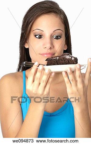 Stock Image - Beautiful Caucasian woman eating a slice of chocolate cake. Fotosearch