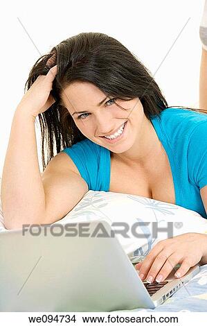 Beautiful Caucasian woman laying in bed working on laptop computer View Large Photo Image Picture - Beautiful Caucasian woman laying in bed working on laptop computer. Fotosearch