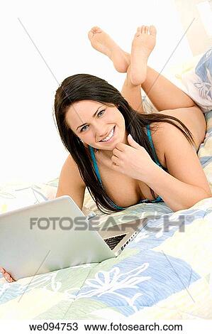 Beautiful Caucasian woman laying in bed working on laptop computer View Large Photo Image Stock Image - Beautiful Caucasian woman laying in bed working on laptop computer. Fotosearch