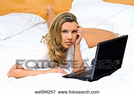 Beautiful caucasian woman laying in bed working on a laptop computer View Large Photo Image Stock Photo - Beautiful caucasian woman laying in bed working on a laptop computer. Fotosearch