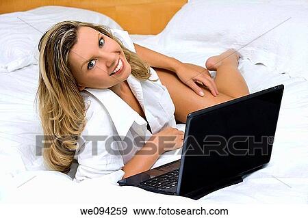 Beautiful caucasian woman laying in bed working on a laptop computer View Large Photo Image Stock Photo - Beautiful caucasian woman laying in bed working on a laptop computer. Fotosearch
