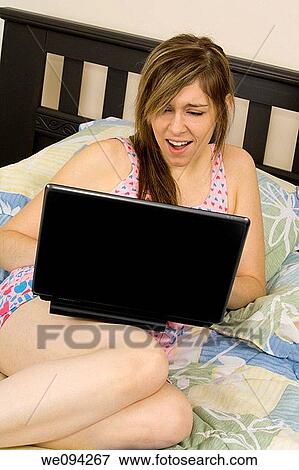 Beautiful caucasian woman laying in bed working on a laptop computer View Large Photo Image Stock Photo - Beautiful caucasian woman laying in bed working on a laptop computer. Fotosearch