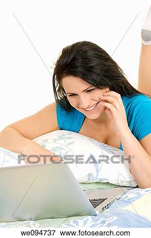 Beautiful Caucasian woman laying in bed working on laptop computer View Large Photo Image Stock Photo - Beautiful Caucasian woman laying in bed working on laptop computer. Fotosearch