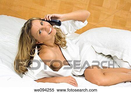Stock Photography - Beautiful caucasian woman laying in bed talking on the phone. Fotosearch