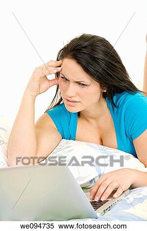 Beautiful Caucasian woman laying in bed working on laptop computer View Large Photo Image Stock Photography - Beautiful Caucasian woman laying in bed working on laptop computer. Fotosearch