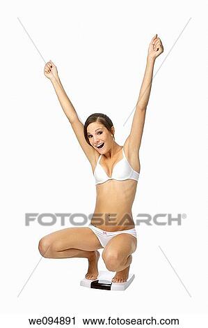 Stock Image - Beautiful Caucasian woman weighting herself and very excited about it. Fotosearch