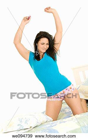 Beautiful woman knelling in bed listening to music View Large Photo Image Stock Photo - Beautiful woman knelling in bed listening to music. Fotosearch