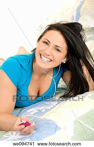 Beautiful woman lying in bed listening to music View Large Photo Image Stock Image - Beautiful woman lying in bed listening to music. Fotosearch
