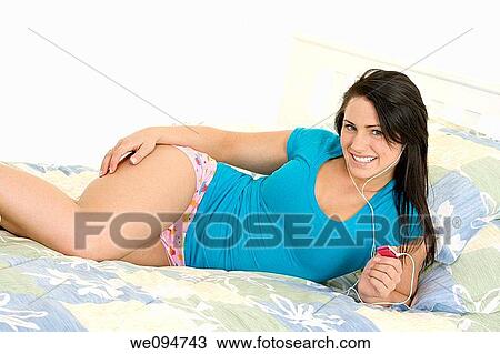 Beautiful woman lying in bed listening to music View Large Photo Image Stock Image - Beautiful woman lying in bed listening to music. Fotosearch