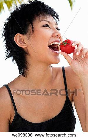 Beautiful young asian woman eating tomato View Large Photo Image Stock Photo - Beautiful young asian woman eating tomato. Fotosearch
