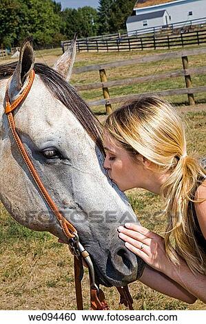 Blonde woman kissing a horse on the nose the is standing in a pasture View Large Photo Image Stock Image - Blonde woman kissing a horse on the nose the is standing in a pasture. Fotosearch