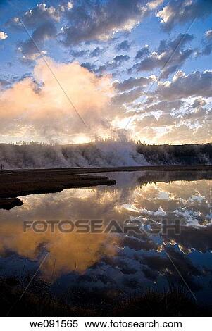 Blue sky and clouds at sunrise reflect in Firehole River, as steam rises from a geothermal area in Yellowstone Park View Large Photo Image Stock Photography - Blue sky and clouds at sunrise reflect in Firehole River, as steam rises from a geothermal area in Yellowstone Park. Fotosearch