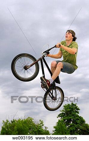 Stock Photography - BMX rider flying in the air against a dark while listening to music. Fotosearch