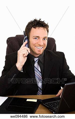 Caucasian businessman setting a desk talking on the phone and smiling View Large Photo Image Stock Photograph - Caucasian businessman setting a desk talking on the phone and smiling. Fotosearch