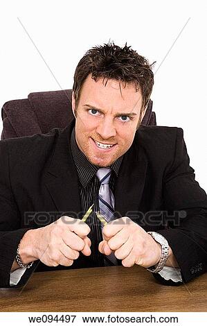 Caucasian businessman setting at a desk and looking very angry and frustrated View Large Photo Image Stock Photo - Caucasian businessman setting at a desk and looking very angry and frustrated. Fotosearch