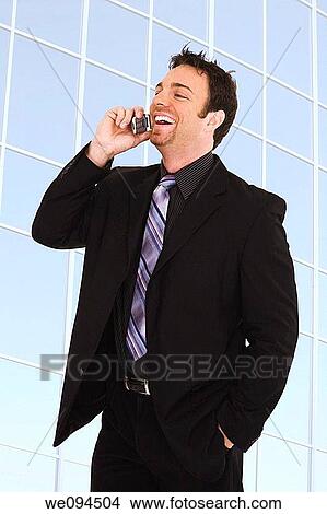 Caucasian businessman standing and talking on the cell phone and smiling View Large Photo Image Picture - Caucasian businessman standing and talking on the cell phone and smiling. Fotosearch