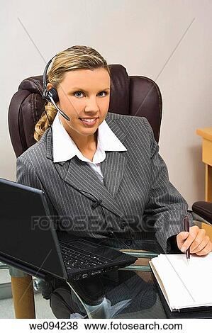 Stock Photo - Caucasian businesswoman in her early 30s setting at a desk going over a day planner. Fotosearch