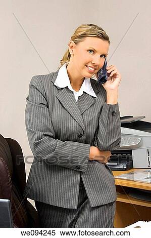 Caucasian businesswoman in her early 30s standing at desk talking ob phone View Large Photo Image Stock Photography - Caucasian businesswoman in her early 30s standing at desk talking ob phone. Fotosearch