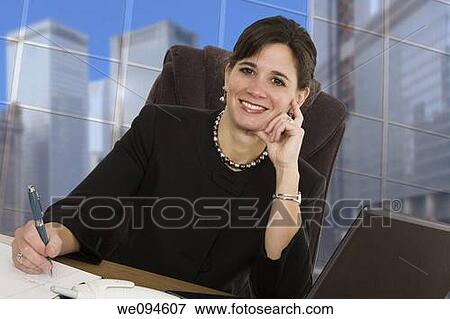 Caucasian businesswoman setting in an office at a desk and smiling View Large Photo Image Stock Photo - Caucasian businesswoman setting in an office at a desk and smiling. Fotosearch
